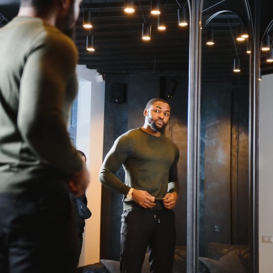 Person with a serious expression looking at their reflection in a mirror, symbolizing self-reflection and internal conflict over jealousy and insecurity.