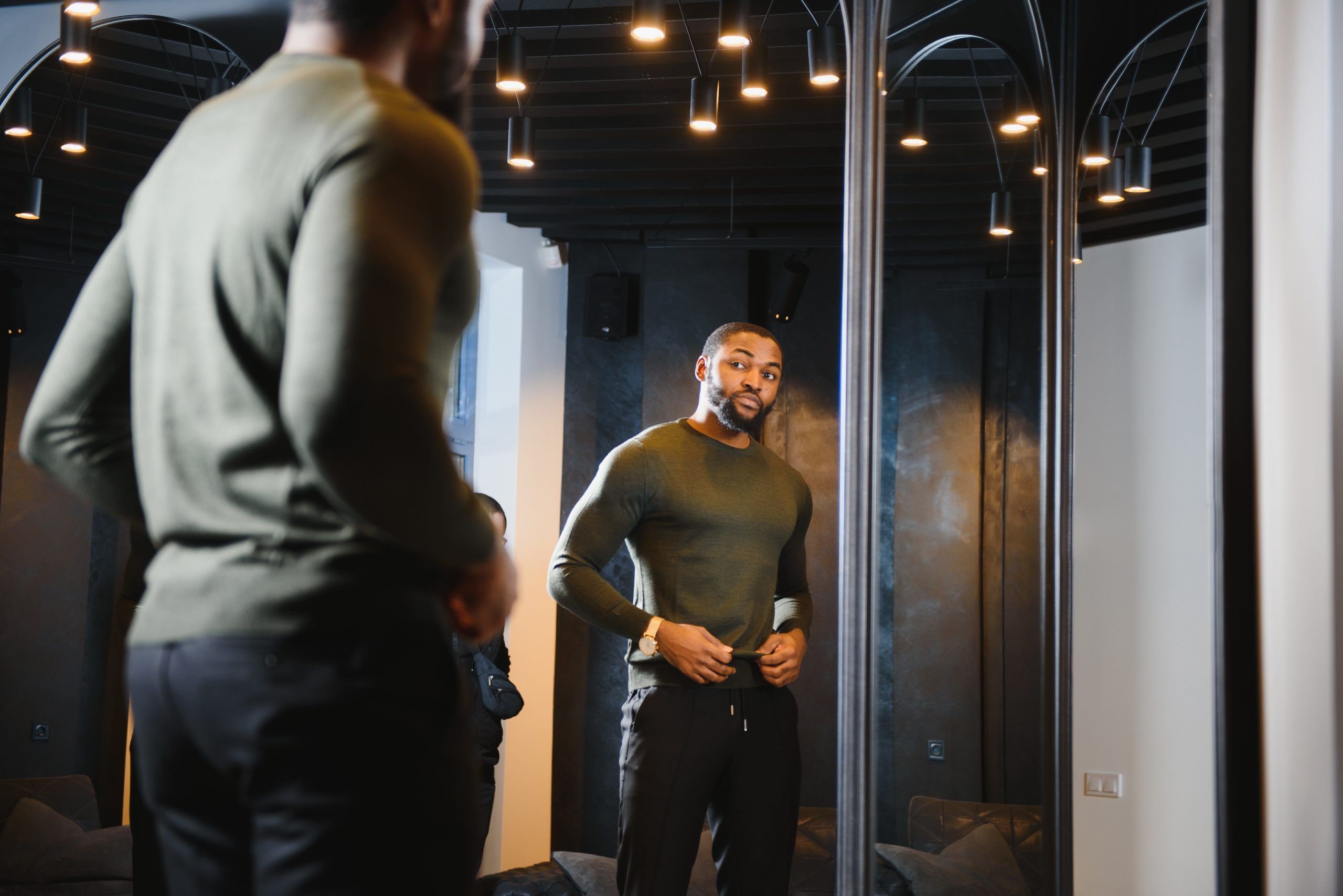 Person with a serious expression looking at their reflection in a mirror, symbolizing self-reflection and internal conflict over jealousy and insecurity.