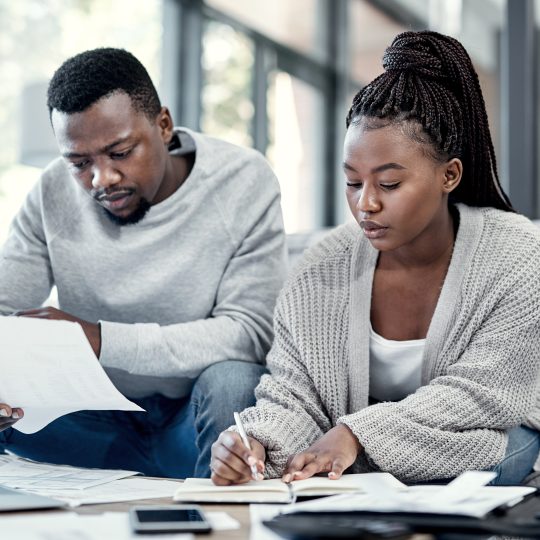 Couple discussing finances and budgeting at a table, looking happy and relieved.