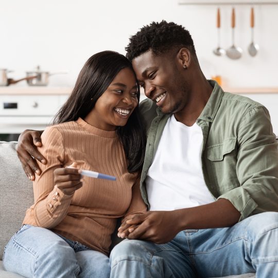 Couple smiling and spending quality time with their baby, representing balance between work, parenthood, and relationship.