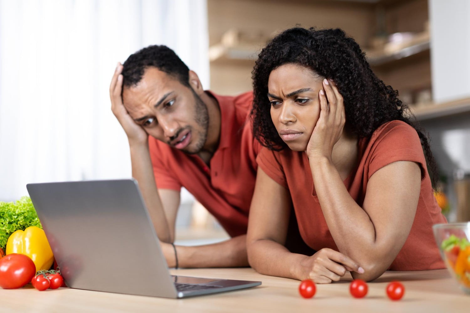 A couple sitting on a couch, one visibly tired while the other offers support