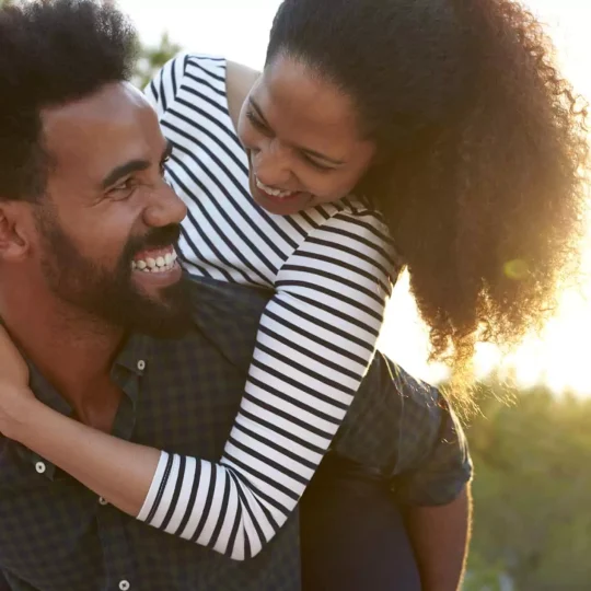 A happy couple laughing together on a cozy couch, showcasing the power of humor in strengthening relationships.