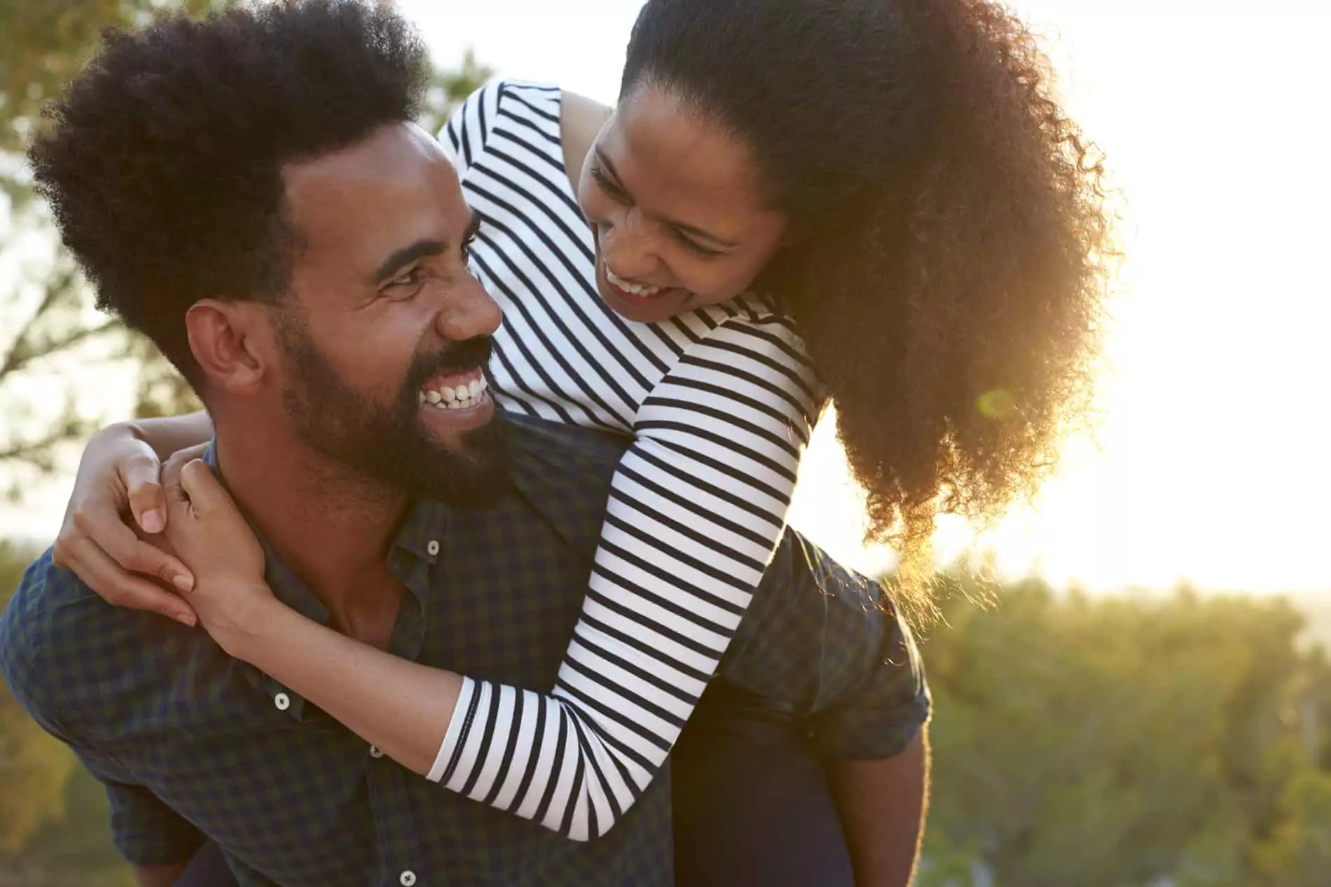 A happy couple laughing together on a cozy couch, showcasing the power of humor in strengthening relationships.